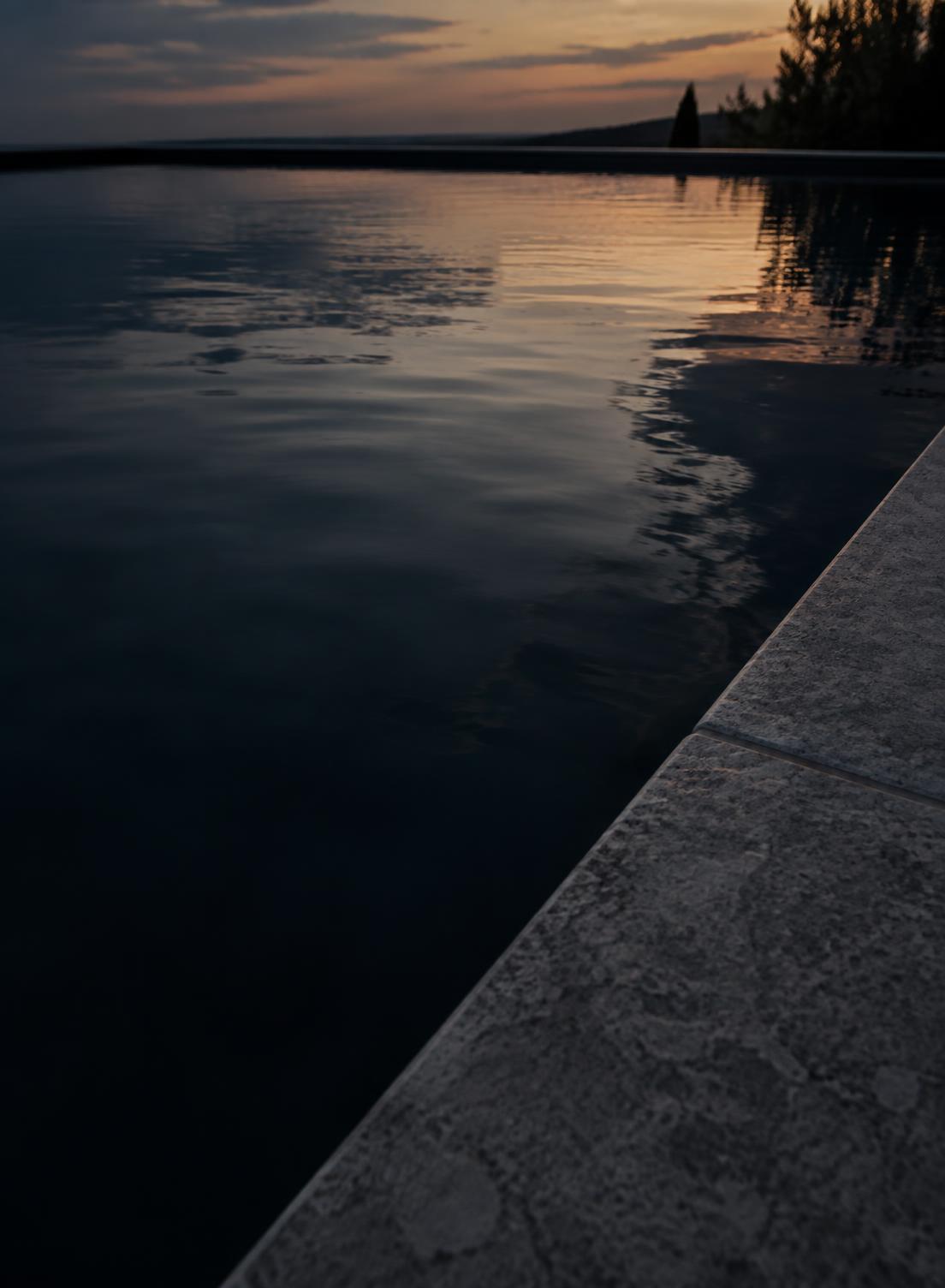 Still pool water meeting a stone edge at dusk