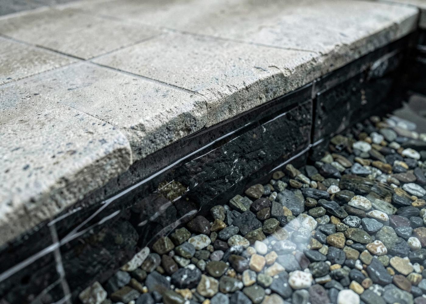 Close view of a new pebble interior finish meeting stone coping